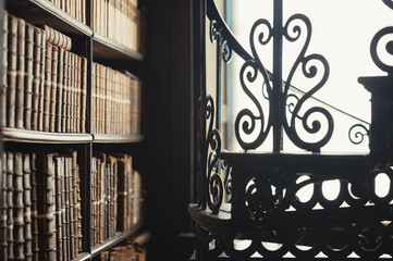 Interior of historic library with bookshelves and wrought iron staircase © ronnybas