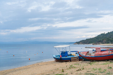 Fototapeta premium Fishing boats on the shore beside a calm sea in the early morning light at a quiet beach location