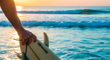 Surfer holding surfboard at sunset on the beach.