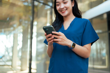 Fototapeta premium Female medical professional smiling and using smartphone