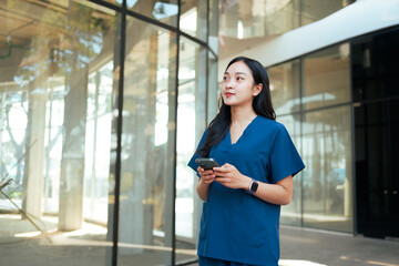 Healthcare worker using smartphone outside modern building