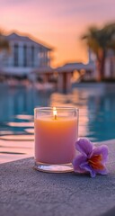 Lit candle beside a purple flower, poolside, with sunset and buildings in the blurred background