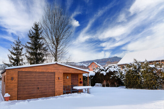 Mountain winter landscape with farm buildings and a garage