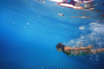 A happy girl dives into the swimming pool. Happy feeling on vacation concept.