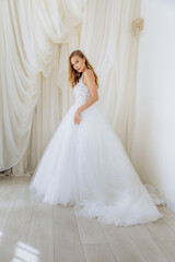 Beautiful girl in a white long luxurious wedding dress. Model bride posing in a gentle location