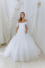 Fototapeta premium Beautiful girl in a white long luxurious wedding dress. Model bride posing in a gentle location