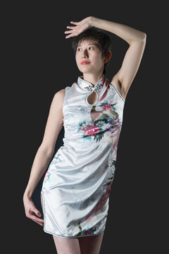 Chinese woman in white ftraditional dress one hand over head stares right