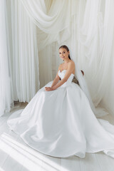 Fototapeta premium Portrait of a bride sitting in a white lush luxury dress with pearls