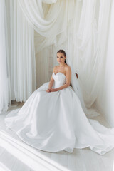 Portrait of a bride sitting in a white lush luxury dress with pearls