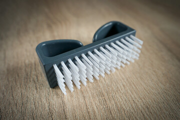 grey plastic nail manicure brush isolated on wooden surface