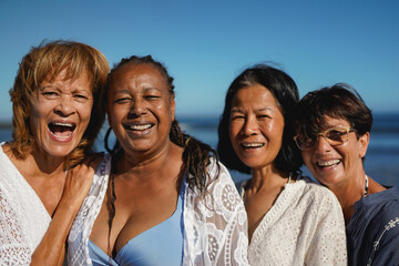 Fototapeta premium Happy multiracial senor women smiling in front of camera during summer beach vacation - Joyful elderly female friends, holiday and tourism concept