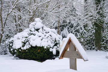 Winterwetter mit reichlich Schnee auf Ästen im Park auf Friedhof