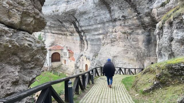 Hombre descubriendo la ermita de San Bernab&eacute; tras las rocas en Ojo Guare&ntilde;a