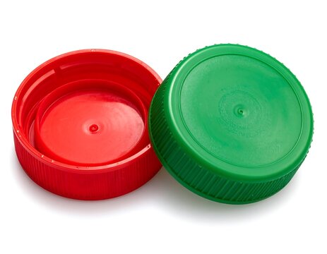 Close-up studio shot of two vibrant plastic bottle caps, one red, the other green, showing inner and outer details