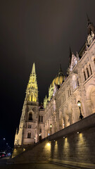 Fototapeta premium Night view of illuminated Gothic-style building with dramatic sky