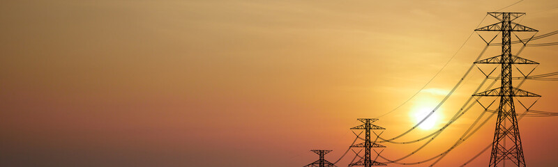 Sunset silhouette of power lines and electricity pylons against a warm, orange sky. A dramatic representation of energy and infrastructure © Stock4u2024 