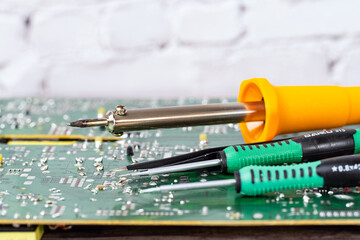 electrical board with a soldering iron and screwdrivers