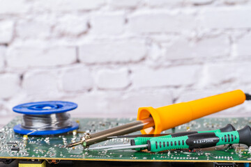 electrical board with a soldering iron and screwdrivers