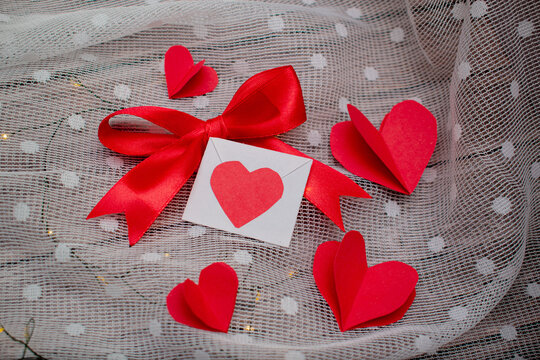 fondo de madera con corazones de papel y una carta de amor con un liston color rojo