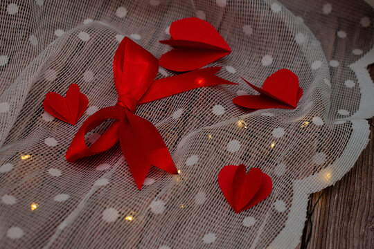 Imagen de un liston rojo en un fondo de tela con madera y luces con corazones de color rojo para san valentin 