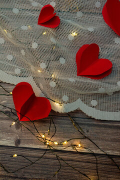 Imagen vertical de corazones rojos de papel en fondo de madera con tela blanca