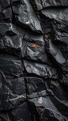 Close-up texture of dark, fractured basalt columns with subtle orange mineral accents.