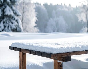 A snow-covered wooden picnic table sits in a bright, wintry landscape with a blurred forest background.