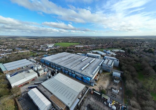 Aerial view of the Colt Data Centre's sprawling campus, a mix of metallic structures and blue accents contrasting with the surrounding winter trees, Welwyn Garden City, United Kingdom.