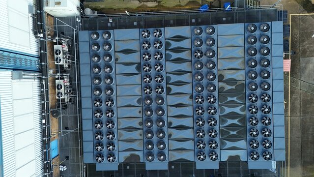 Aerial view of a dense assembly of cooling units, their dark fans contrasting sharply against the lighter rooftops, Colt Data Centre services, Welwyn Garden City, United Kingdom.