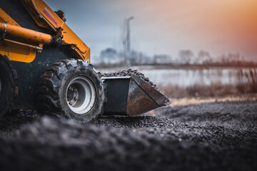Mini loader with bucket. Mini loader is preparing the terrain. Mini wheel loader is spreading the stone onto the work surface. © Peter