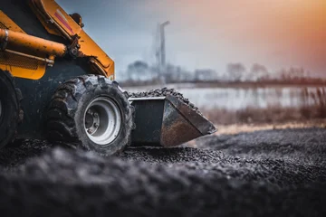 Fotobehang Vrachtwagen Mini loader with bucket. Mini loader is preparing the terrain. Mini wheel loader is spreading the stone onto the work surface.  © Peter