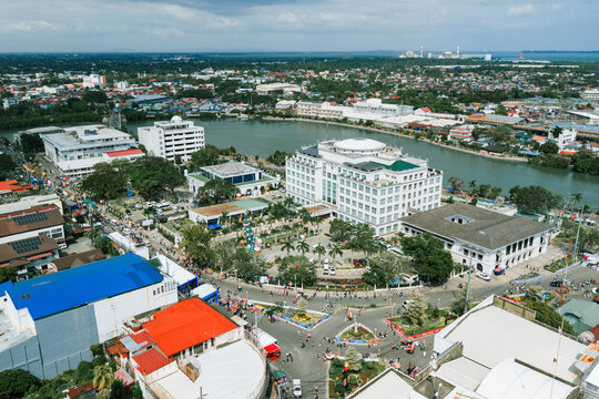 Aerial view of the vibrant cityscape meeting the tranquil river, where white buildings stand out against the lush greenery, Iloilo City, Western Visayas, Philippines.