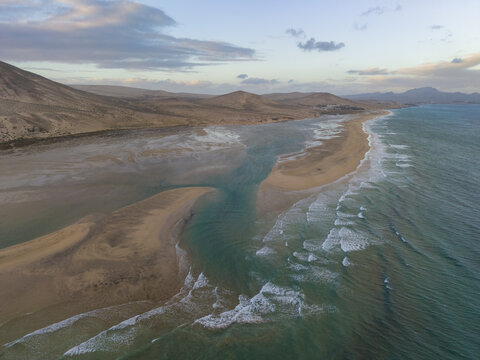 Aerial view of turquoise waters meet golden sandy beach and the lagoon framed by arid mountains in the peninsula, Jand&Atilde;&shy;a Natural Park, Fuerteventura, Canary Islands, Spain.