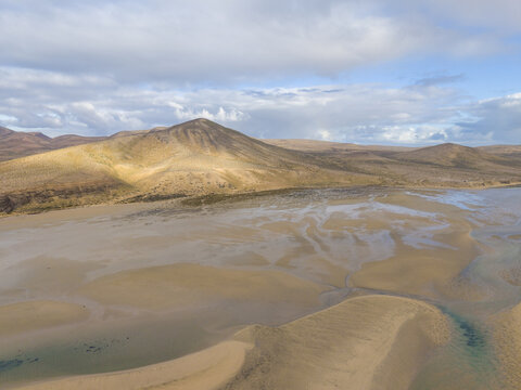 Aerial view of the vast, sandy expanse of Jand&Atilde;&shy;a lagoon meeting the Atlantic, with distant mountains under a sky of soft clouds, Jand&Atilde;&shy;a Natural Park, Fuerteventura, Canary Islands, Spain.