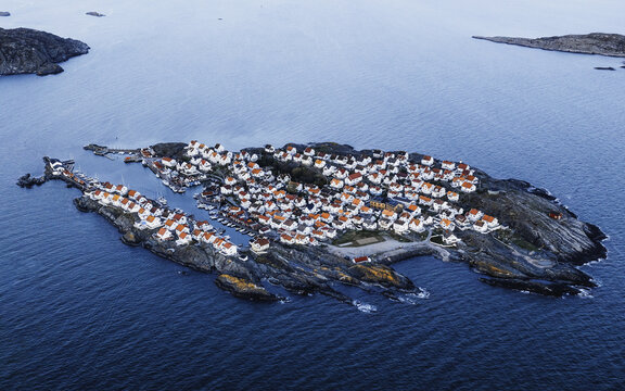Aerial view of &Atilde;&hellip;stol island's clustered white houses with red roofs clinging to the rugged, rocky coastline, contrasting with the deep blue sea, &Atilde;&hellip;stol, V&Atilde;&curren;stra G&Atilde;&para;taland County, Sweden.