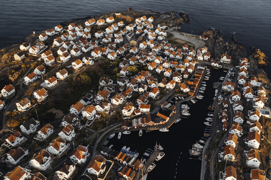 Aerial view of charming red-roofed houses clustering along the rocky coastline, boats resting in the calm harbor waters, &Atilde;&hellip;stol, V&Atilde;&curren;stra G&Atilde;&para;taland County, Sweden.