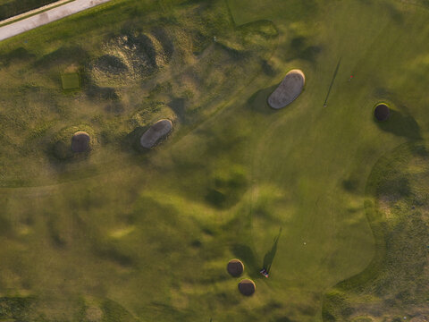 Aerial view of the verdant golf course with its contrasting bunkers casting long shadows in the evening light, St Andrews, Scotland, United Kingdom.