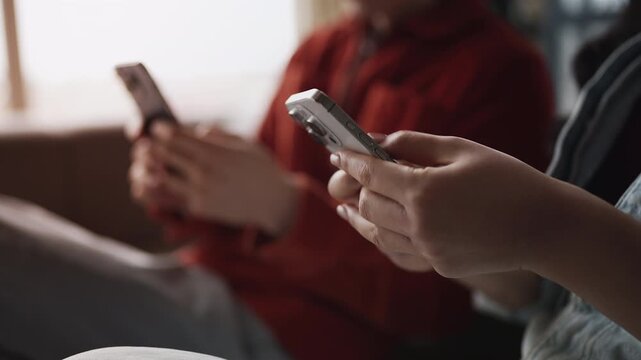 Close-up of young man and woman scrolling on cellphones, digital media addiction