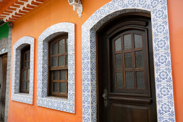 Obraz premium Wooden windows and doors of a well-preserved old house painted orange, with tile details around the windows and door
