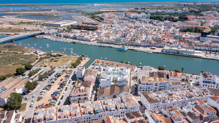Naklejka premium Tavira in Algarve shows a Gilao river lined with boats and buildings. The scene captures the town's layout and architecture from a high viewpoint