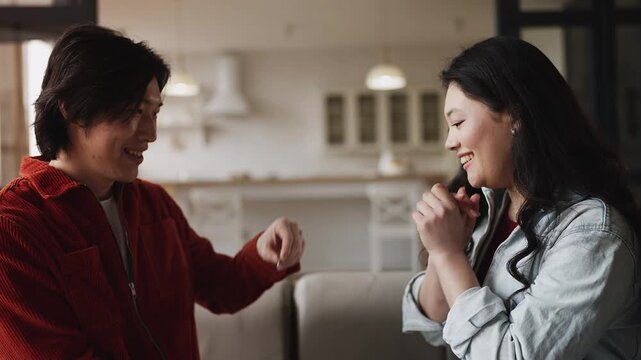 Korean man presenting engagement ring to happy girlfriend, proposing marriage