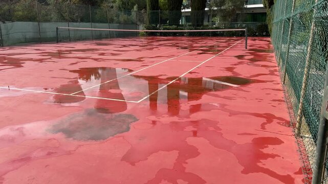 Wet Surface of Clay Tennis Court with Large Rain Water Puddle 