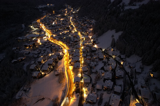 Aerial view of a village nestled in a snow-covered valley, lights twinkling like stars against the dark, cold landscape, Champ&Atilde;&copy;ry, Valais, Switzerland.