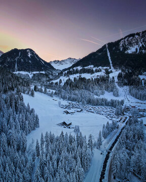 Aerial view of snow-laden pines and chalets nestle in the valley, with peaks kissed by the fading alpine light, Champ&Atilde;&copy;ry, Valais, Switzerland.