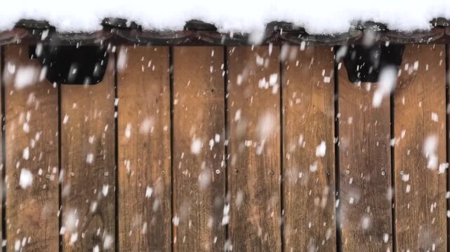 Starker Schneefall vor schneebedecktem Dach und Holzwand, Scheune, Winter