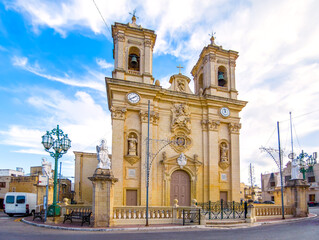 Obraz premium St. Bartholomew Church in Gharghur, Malta, with baroque architecture and saints statues under blue sky