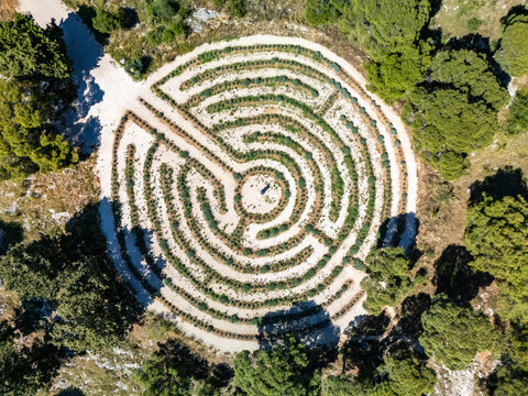 Aerial view of the circular lavender labyrinth, a mesmerizing pattern of pathways and verdant hedges, set against the rugged terrain, Rogoznica, Croatia.