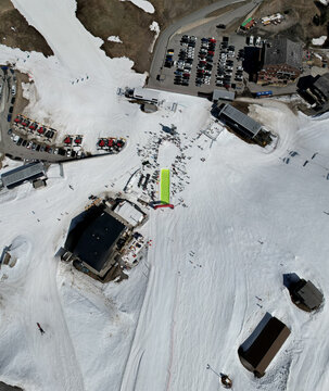 Aerial view of a snowy landscape dotted with buildings and parked cars, highlighting the contrast between white snow and dark structures, Val-d'Illiez, Valais, Switzerland.