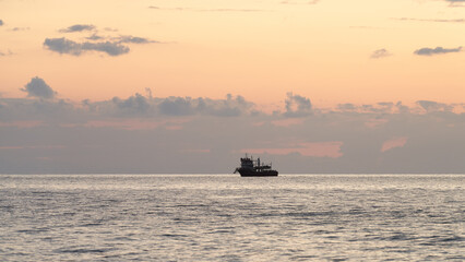 The outline of a tourist ship on the horizon of a seascape at sunset. Copy space.