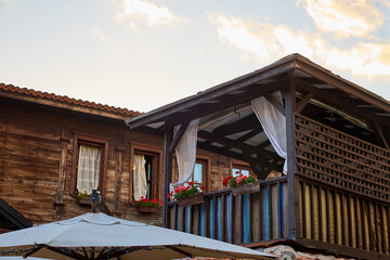 Naklejka premium Charming rustic wooden house with balcony drapes and flower boxes at sunset
